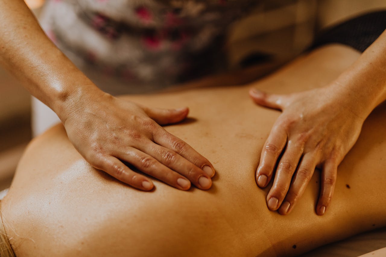Julie Molines NATUROPATHE à REYNIèS 82 Close-up of hands giving a soothing back massage in a calm setting.