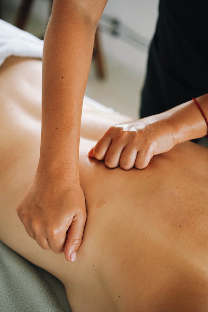 Julie Molines NATUROPATHE à REYNIèS 82 Close-up of a relaxing therapeutic massage focusing on back muscles in a tranquil spa environment.